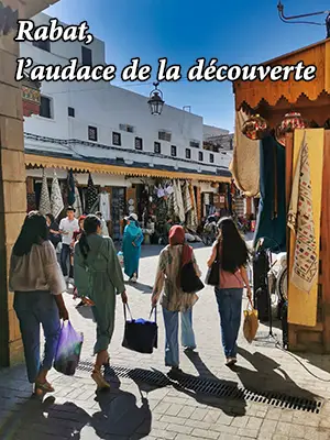 Rue commerçante animée dans la médina de Rabat avec des passants et des boutiques traditionnelles sous auvents
